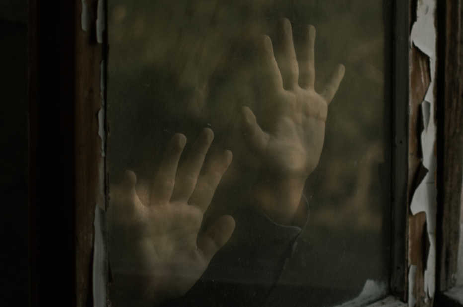Imagen representa la lucha, unas manos en un cristal dejando marcas claras de querer salir